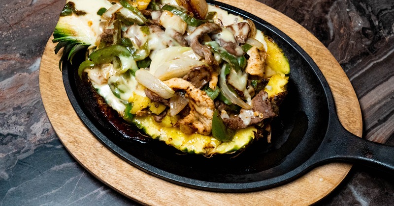Fajita Tropical featuring grilled meats and vegetables served inside a hollowed-out pineapple