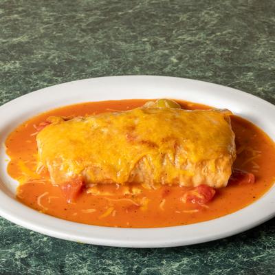 Burrito topped with melted cheese and red sauce, served on a white plate.