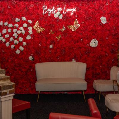 Interior decorated with an artificial flower wall backdrop with neon sign.