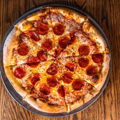 Top down view of pepperoni pizza on a wooden table.