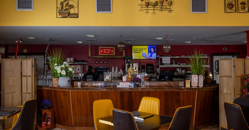 Interior with a semi-circular wooden counter, decorative items and mustard-yellow chairs