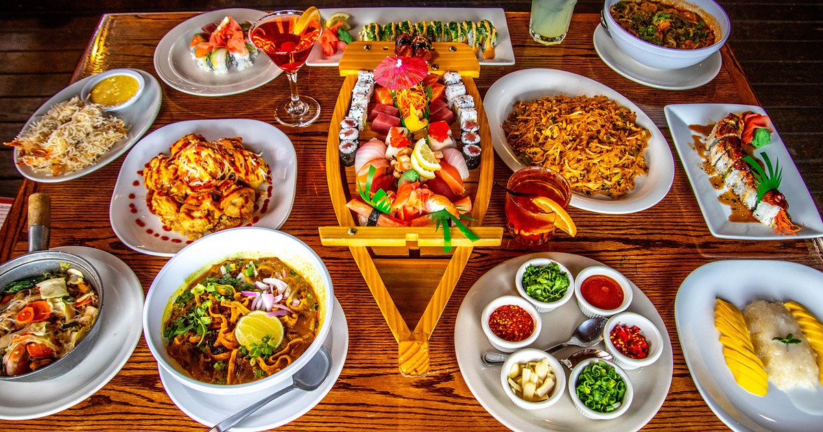 Sushi boat platter served on the table beside various dishes and cocktails