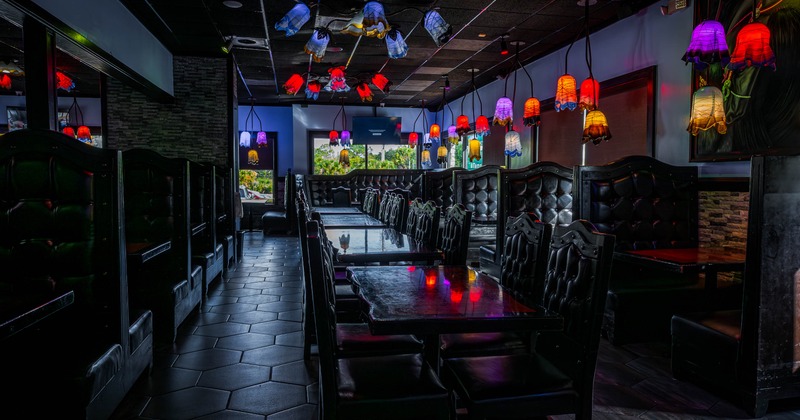 Dimly lit restaurant interior with colorful pendant lamps and cushioned booths