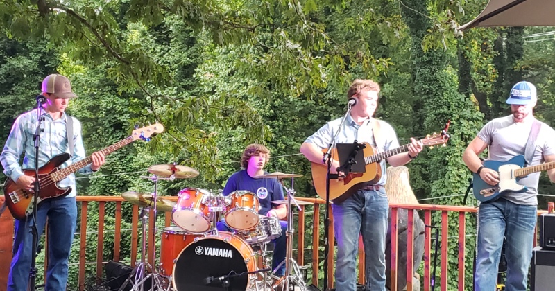 Band performing outdoors on a wooden deck