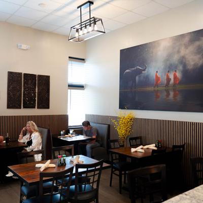 Interior, modern decor with  art on the walls, tables and chairs, guests sitting in booths.