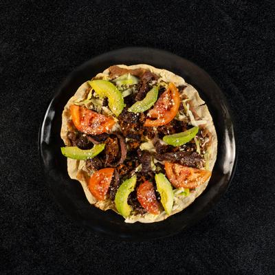 Tlayuda Mole topped with meat, avocado and tomato slices.