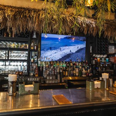 Tropical-style bar with liquor bottles and a TV.