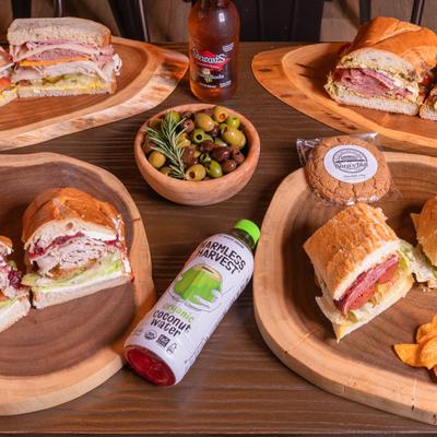 Assorted sandwich, beverages, and sides displayed on a table.