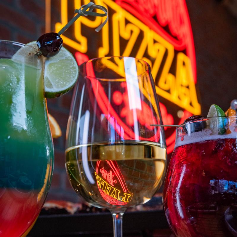 Side view of different drinks, neon sign in the back.