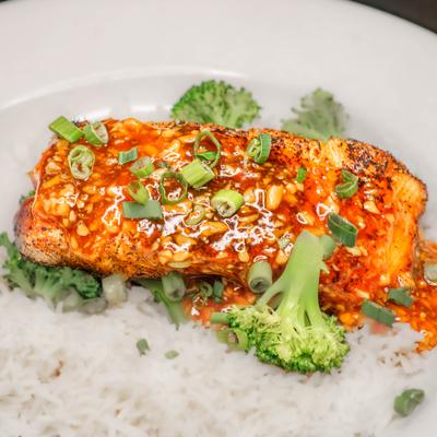 Glazed salmon served over rice with broccoli.