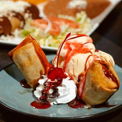 Fried ice cream sundae with whipped cream, sauce drizzle and a cherry.