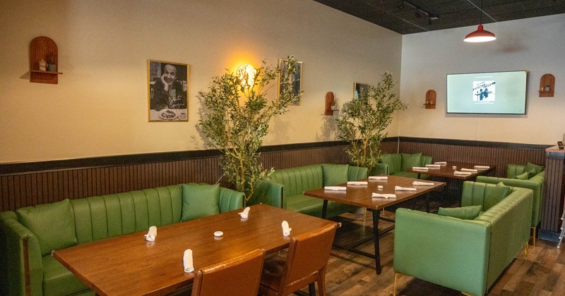 Dining area with green booth seating, wooden tables and decorative wall photos