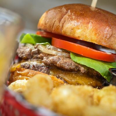 Burger served with tots, close up.