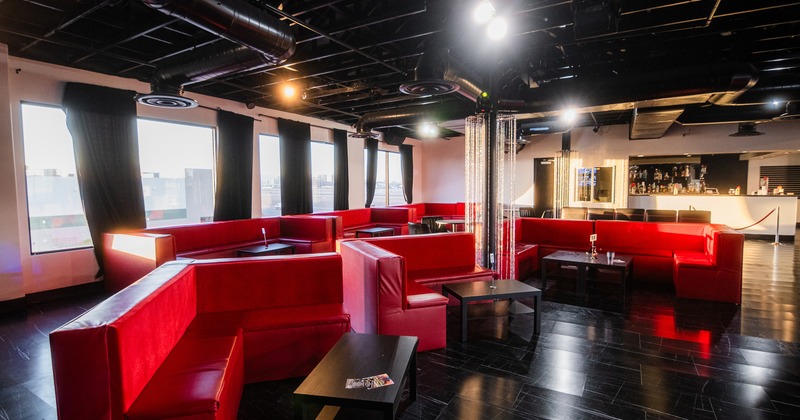 Interior of a modern lounge area with dark flooring and red upholstered booth seating