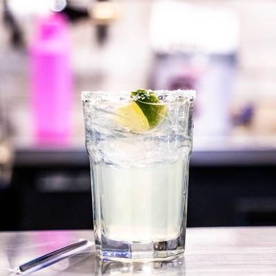 A hazy cocktail garnished with a lime wedge sits on counter.