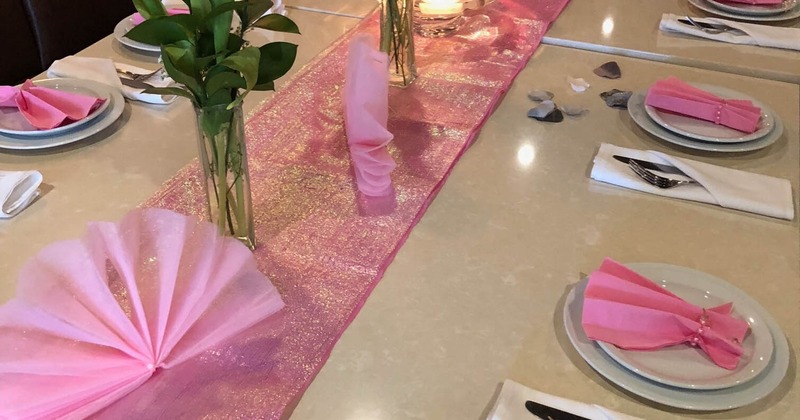 A beautifully arranged table featuring pink napkins and elegant place settings