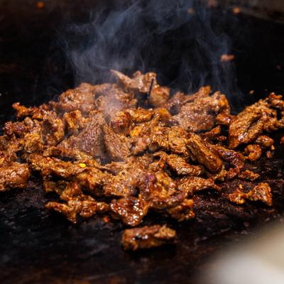 Marinated beef being cooked on a griddle.