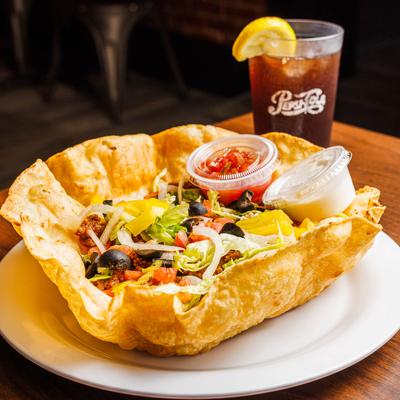 Taco salad in a tortilla bowl with a soda.