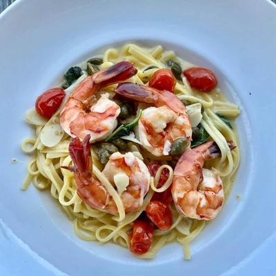 Shrimp scampi served over linguine with cherry tomatoes and capers.