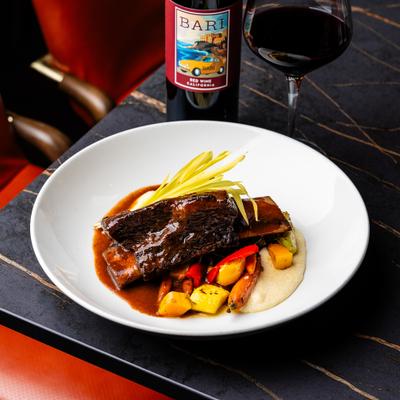 A red wine braised beef short rib dish plated with side vegetables.