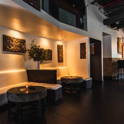 Modern restaurant interior with textured wall art, lounge seating and dark tables.