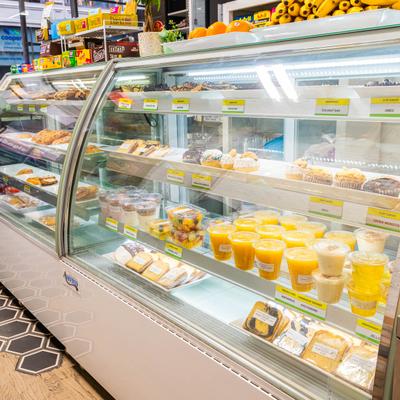 Display case with fruit cups, juices, and pastries.