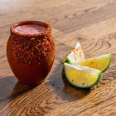 Mexican Candy Shot with spiced rim, placed on a table with lime wedges.