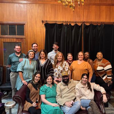 A group of people posing together in a warmly-lit room with wooden paneling.