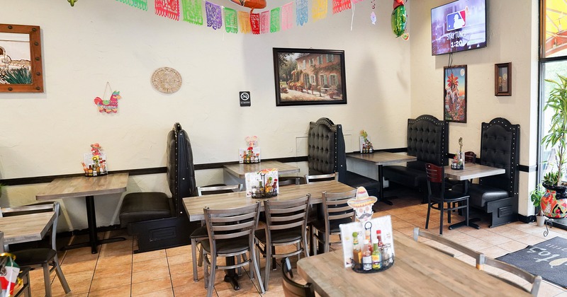 Interior of a cozy dining area with dining tables, chairs and upholstered booths along the wall