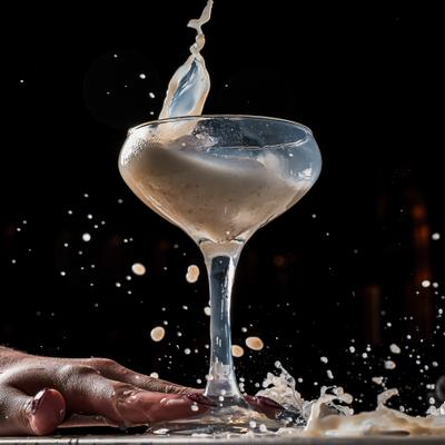 Cocktail with a dramatic splash, served in a stemmed coupe glass.