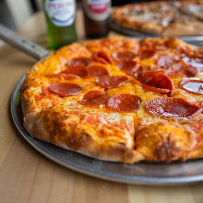 Whole Pepperoni pizza sliced and served on a metal tray.