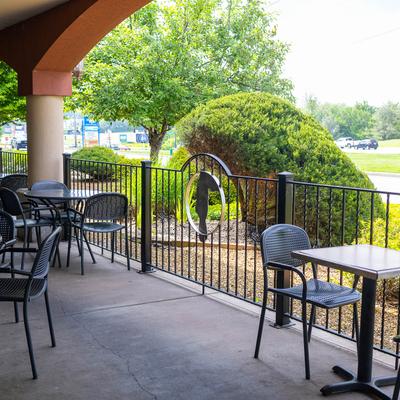 Outdoor patio with black metal furniture and landscaped greenery.