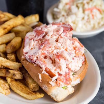 Lobster roll with sides of fries and coleslaw.