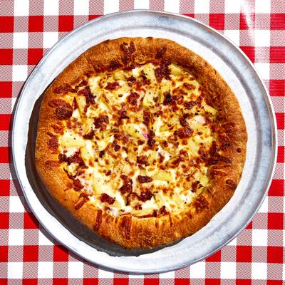 Cheese pizza on a metal pan atop a red and white checkered table, top down view.