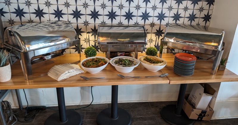 A buffet setup including chafing dishes and bowls containing salads or sides