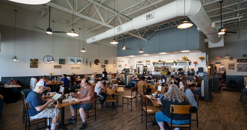 A restaurant full of people, tables and chairs