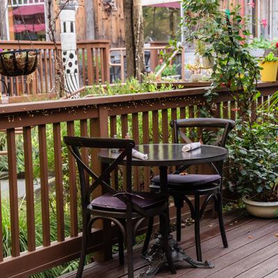 Outdoor patio with wooden fence and deck, potted plants and table seating.