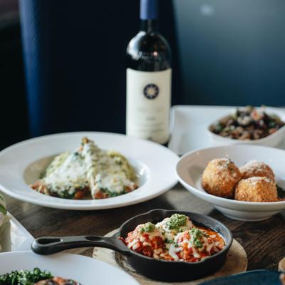 Assorted dishes and a bottle of wine spread on a wooden table.