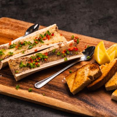 Roasted beef bone marrow served with garlic bread and carved lemon.