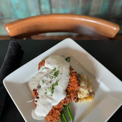Fried chicken topped with white gravy, served over green beans and mashed potatoes.