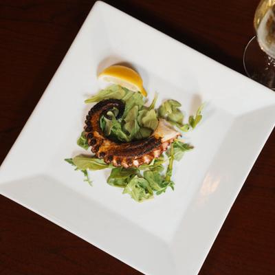 Grilled octopus tentacle with arugula.