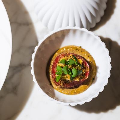 A gourmet dish in a white bowl on a marble surface.