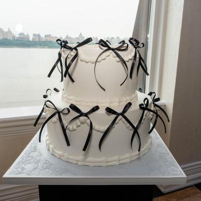 White tiered cake decorated with black ribbons.