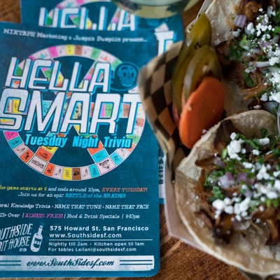 Flyer promoting a recurring Tuesday Night Trivia event, partial view of tacos.
