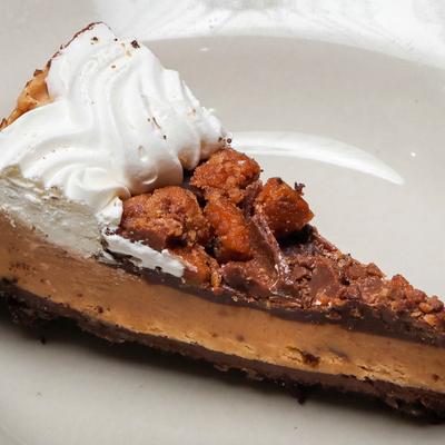 Slice of Peanut Fudge Pie decorated with whipped cream.