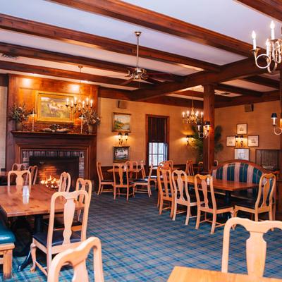 Interior, seating area with tables and chairs, fireplace, wall pictures, chandeliers.