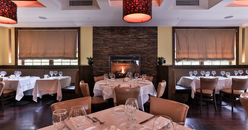 Cozy interior with a stone fireplace, white-clothed tables and warm lighting.