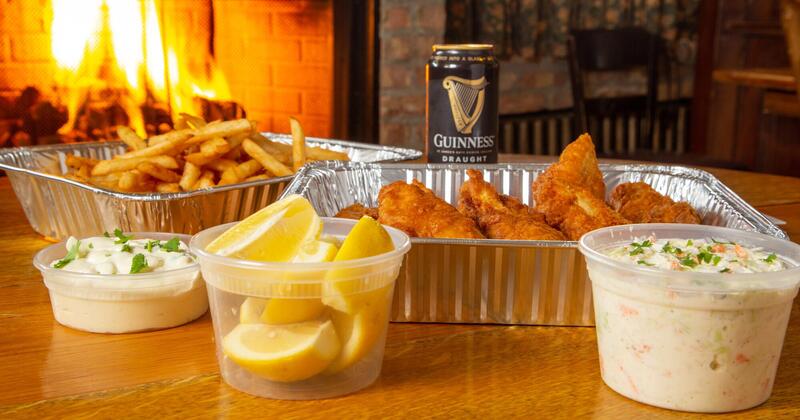 Fish and chips, coleslaw, lemon wedges and a can of Guinness