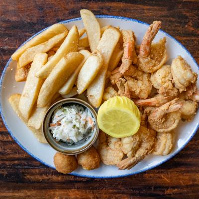 Plate of fried shrimp and steak fries with coleslaw and lemon.