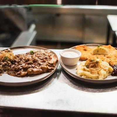 Wiener Schnitzel beside a plate of creamy mushroom dish.